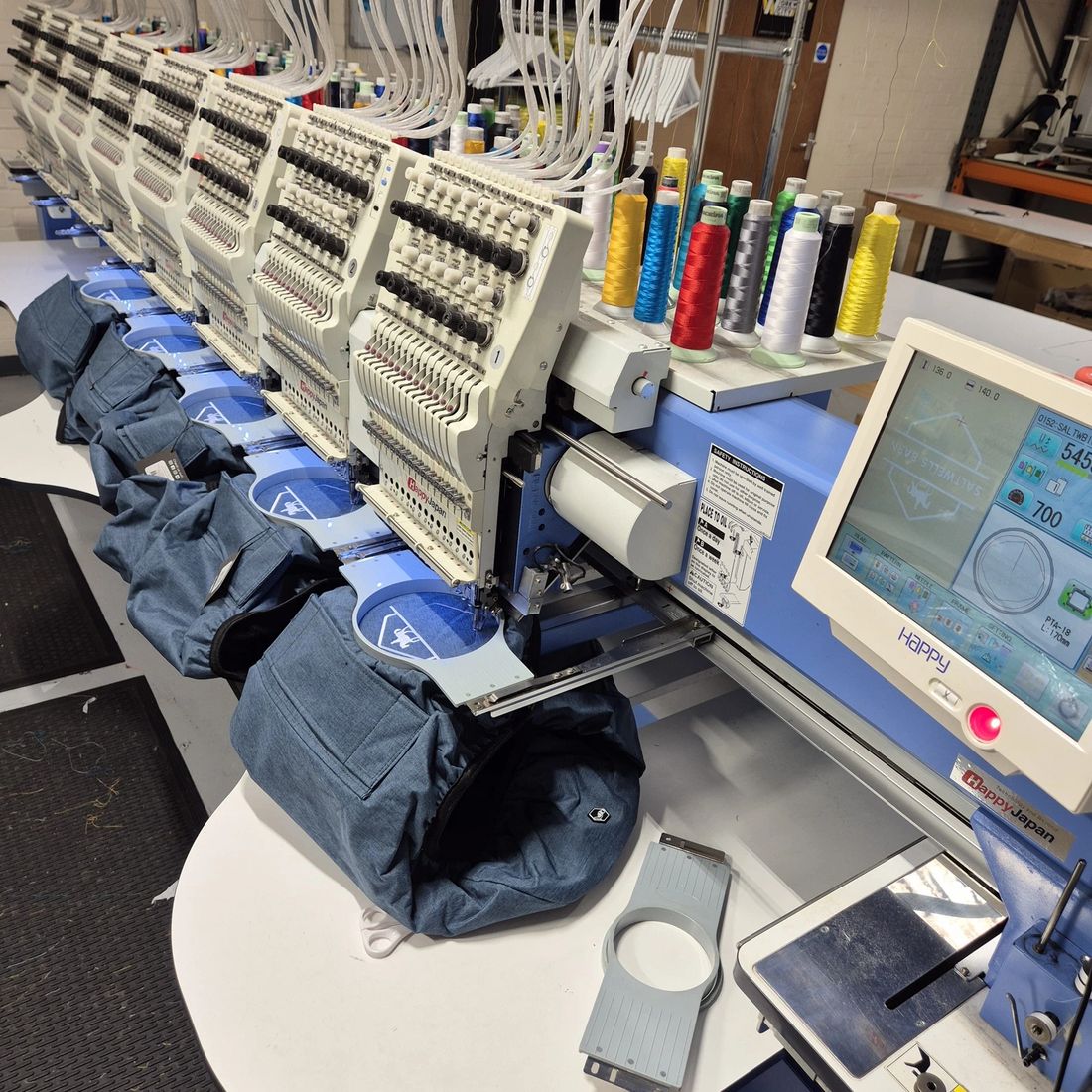 Multi head Happy Japan embroidery machine stitching bags in the Stitches 2 Impress studio